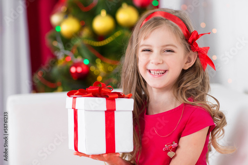 Photo: Adorable curly girl with Christmas present Adorable curly girl with Christmas present