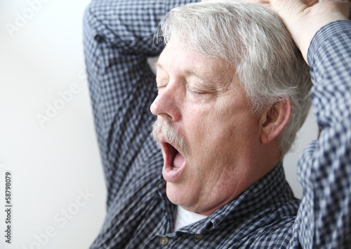 Photo: tired senior man stretches and yawns tired senior man stretches and yawns