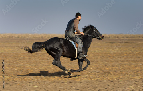Photo: Man riding black horse on field Man riding black horse on field