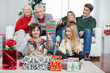 Boy Holding Christmas Gift With Family In House Boy Holding Christmas Gift With Family In House