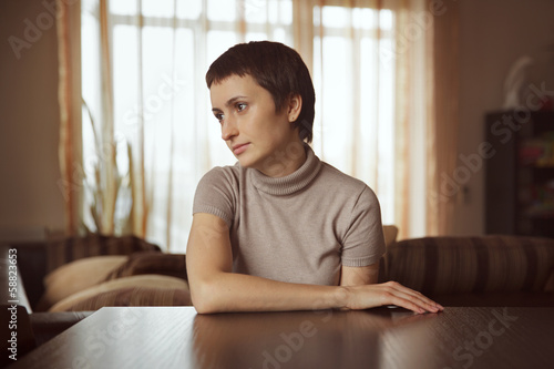 Photo: Beautiful young woman sitting at table Beautiful young woman sitting at table