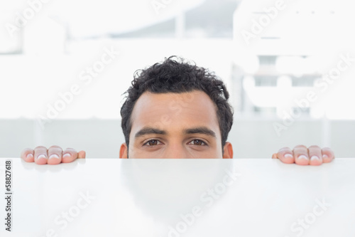 Photo: Businessman peeking behind the desk at office Businessman peeking behind the desk at office