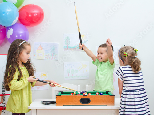 Photo: Children playing mini billiard at playroom Children playing mini billiard at playroom