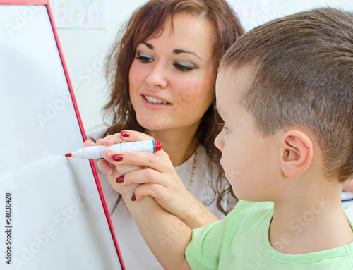 Photo: Little boy with teacher near whiteboard Little boy with teacher near whiteboard