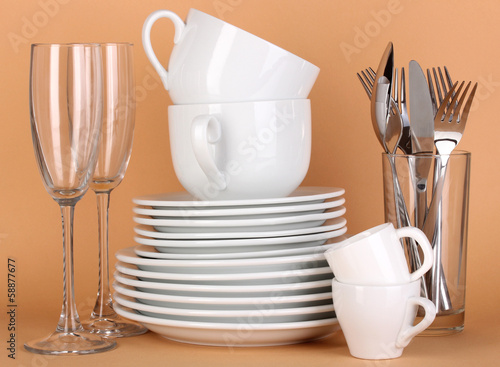 Photo: Clean white dishes on beige background Clean white dishes on beige background