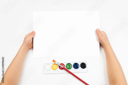 Photo: Blank sheet in child hand and watercolor paint Blank sheet in child hand and watercolor paint