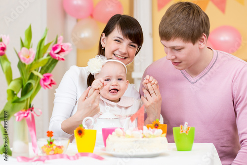Photo: young family celebrating first birthday of baby girl young family celebrating first birthday of baby girl