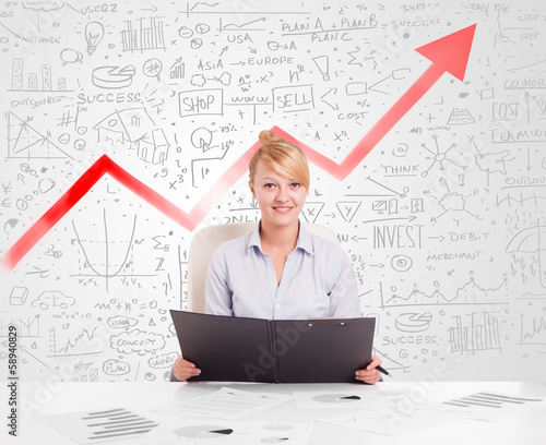 Photo: Business woman sitting at table with market diagrams Business woman sitting at table with market diagrams