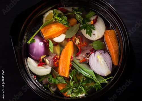 Photo: Fresh soup in a pot on black background Fresh soup in a pot on black background