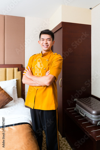 Photo: Asian Chinese porter bringing suitcase to luxury hotel room Asian Chinese porter bringing suitcase to luxury hotel room