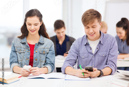 Photo: students looking into smartphone at school students looking into smartphone at school