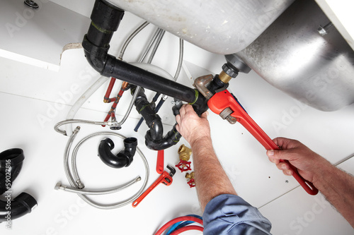 Photo: Hands of Plumber with a wrench. Hands of Plumber with a wrench.