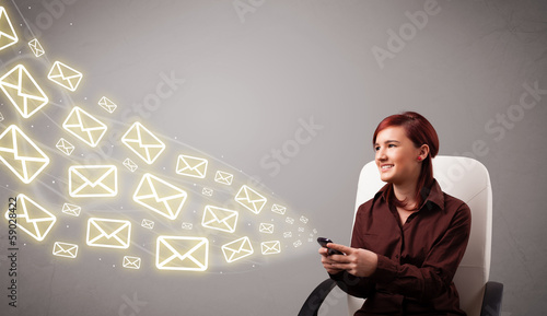 Photo: attractive young lady holding a phone with message icons attractive young lady holding a phone with message icons