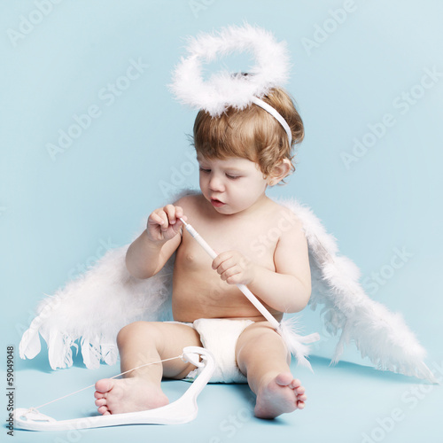 Photo: Beautiful little angel on blue background Beautiful little angel on blue background