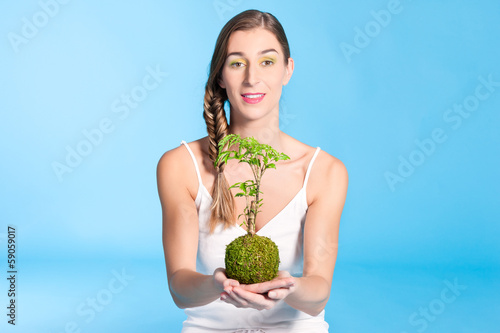 Photo: Young Woman holding a small tree Young Woman holding a small tree