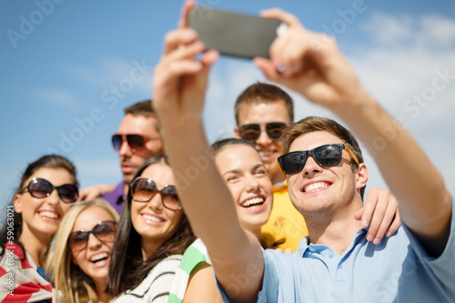 Photo: group of friends taking picture with smartphone group of friends taking picture with smartphone