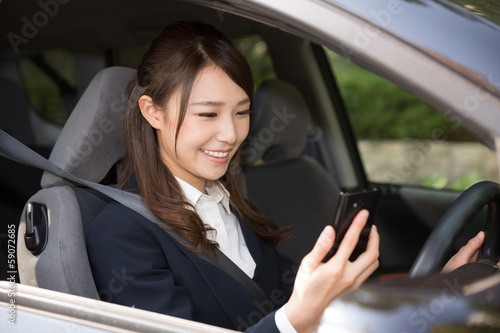 Photo: 車でスマートフォンを見る女性 ビジネス 車でスマートフォンを見る女性 ビジネス