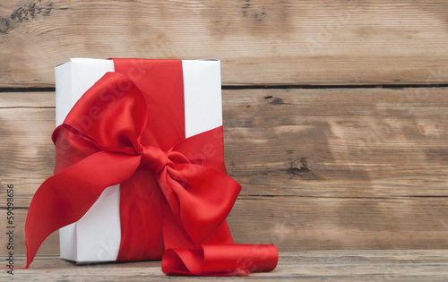 Photo: paper gift box wrapped with red ribbon on wood background paper gift box wrapped with red ribbon on wood background
