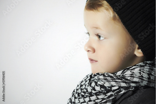 Photo: fashionable little boy in scarf and cap.winter children fashionable little boy in scarf and cap.winter children