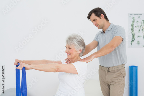 Photo: Male therapist assisting senior woman with exercises Male therapist assisting senior woman with exercises