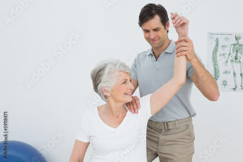 Photo: Physiotherapist stretching a smiling senior woman's arm Physiotherapist stretching a smiling senior woman's arm