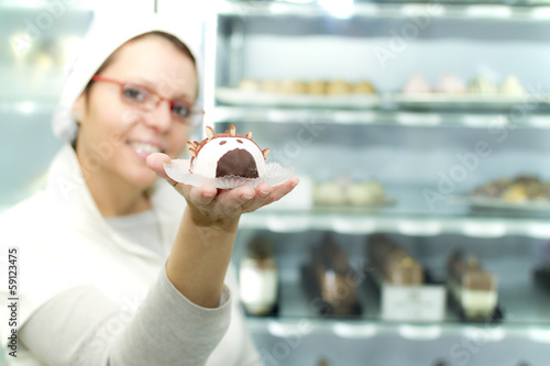 Photo: Woman with pastry in hand in Ice Cream store Woman with pastry in hand in Ice Cream store