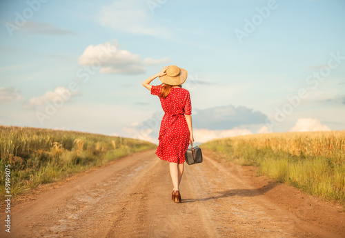 Photo: Redhead girl with suitcase at outdoor. Redhead girl with suitcase at outdoor.