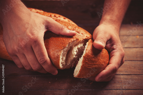 Photo: Baker's hands with a bread. Photo with high contrast Baker's hands with a bread. Photo with high contrast