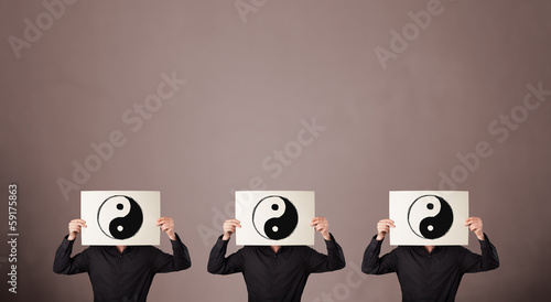 Photo: Handsome people in formal gesturing with yin yang sign on cardbo Handsome people in formal gesturing with yin yang sign on cardbo