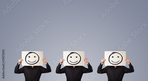 Photo: Men in suit gesturing with sketched smiley faces on cardboard Men in suit gesturing with sketched smiley faces on cardboard