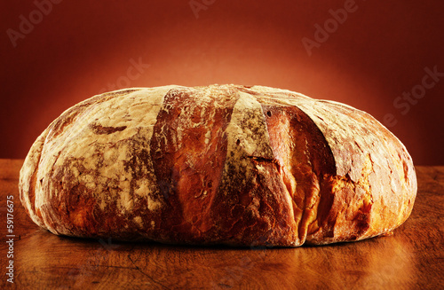 Photo: Large loaf of traditionally baked bread on the table Large loaf of traditionally baked bread on the table