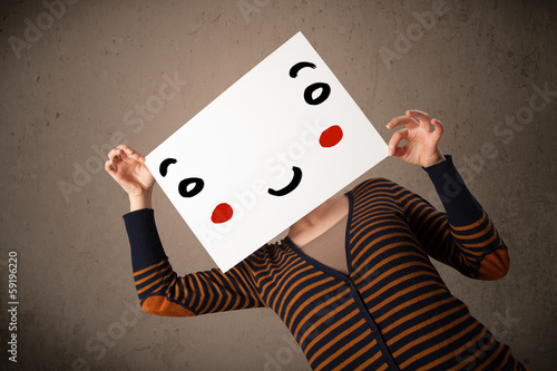Photo: Woman holding a cardboard with a smiley face on it Woman holding a cardboard with a smiley face on it