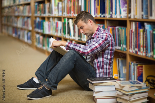Photo: Student sitting on library floor reading Student sitting on library floor reading