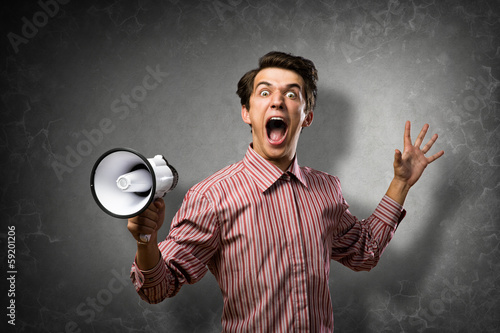 Photo: Portrait of a young man shouting using megaphone Portrait of a young man shouting using megaphone