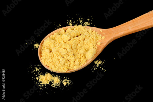Photo: Mustard Powder in Wooden Spoon on Black Background Mustard Powder in Wooden Spoon on Black Background