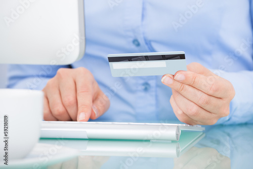 Photo: Person Holding Credit Card Using Computer Person Holding Credit Card Using Computer
