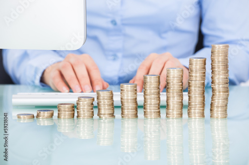 Photo: Coins Stacked On Desk In Front Of Businesswoman Coins Stacked On Desk In Front Of Businesswoman