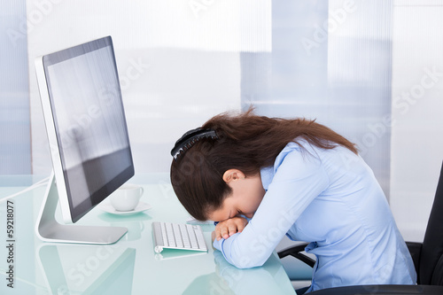 Photo: Tired Businesswoman Leaning At Office Desk Tired Businesswoman Leaning At Office Desk