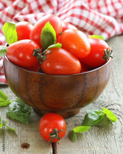 Photo: cherry tomatoes with basil leaves in a wooden bowl cherry tomatoes with basil leaves in a wooden bowl