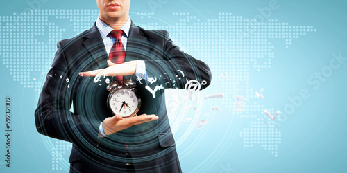 Photo: Business man holding alarmclock Business man holding alarmclock