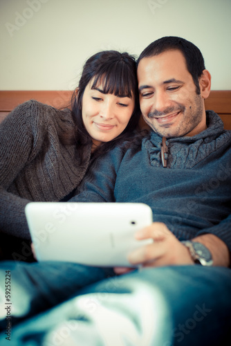 Photo: couple in love on the bed using tablet couple in love on the bed using tablet
