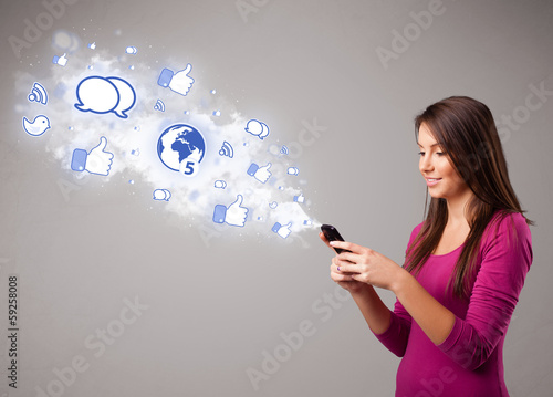 Photo: Pretty young girl holding a phone with social media icons Pretty young girl holding a phone with social media icons