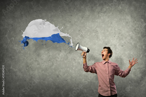 Photo: Portrait of a young man shouting using megaphone Portrait of a young man shouting using megaphone