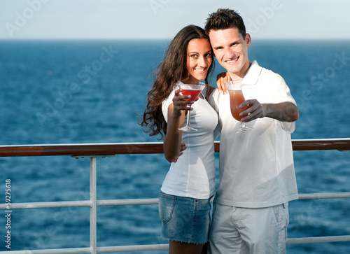 Photo: Happy couple with cocktails standing outside with sea view Happy couple with cocktails standing outside with sea view