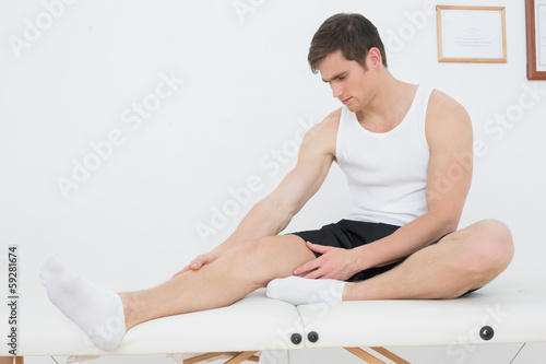 Photo: Young man sitting on examination table in medical office Young man sitting on examination table in medical office