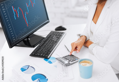 Photo: woman hand with calculator, papers and monitor woman hand with calculator, papers and monitor
