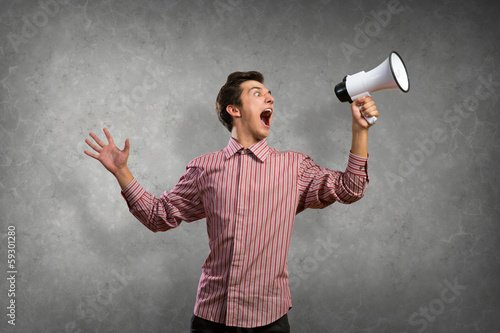 Photo: Portrait of a young man shouting using megaphone Portrait of a young man shouting using megaphone