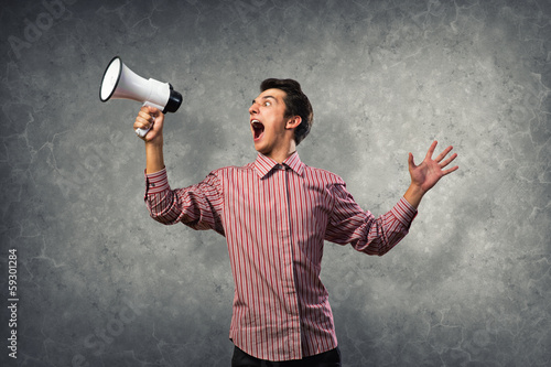 Photo: Portrait of a young man shouting using megaphone Portrait of a young man shouting using megaphone
