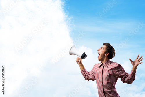 Photo: Portrait of a young man shouting using megaphone Portrait of a young man shouting using megaphone