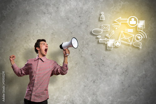 Photo: Portrait of a young man shouting using megaphone Portrait of a young man shouting using megaphone